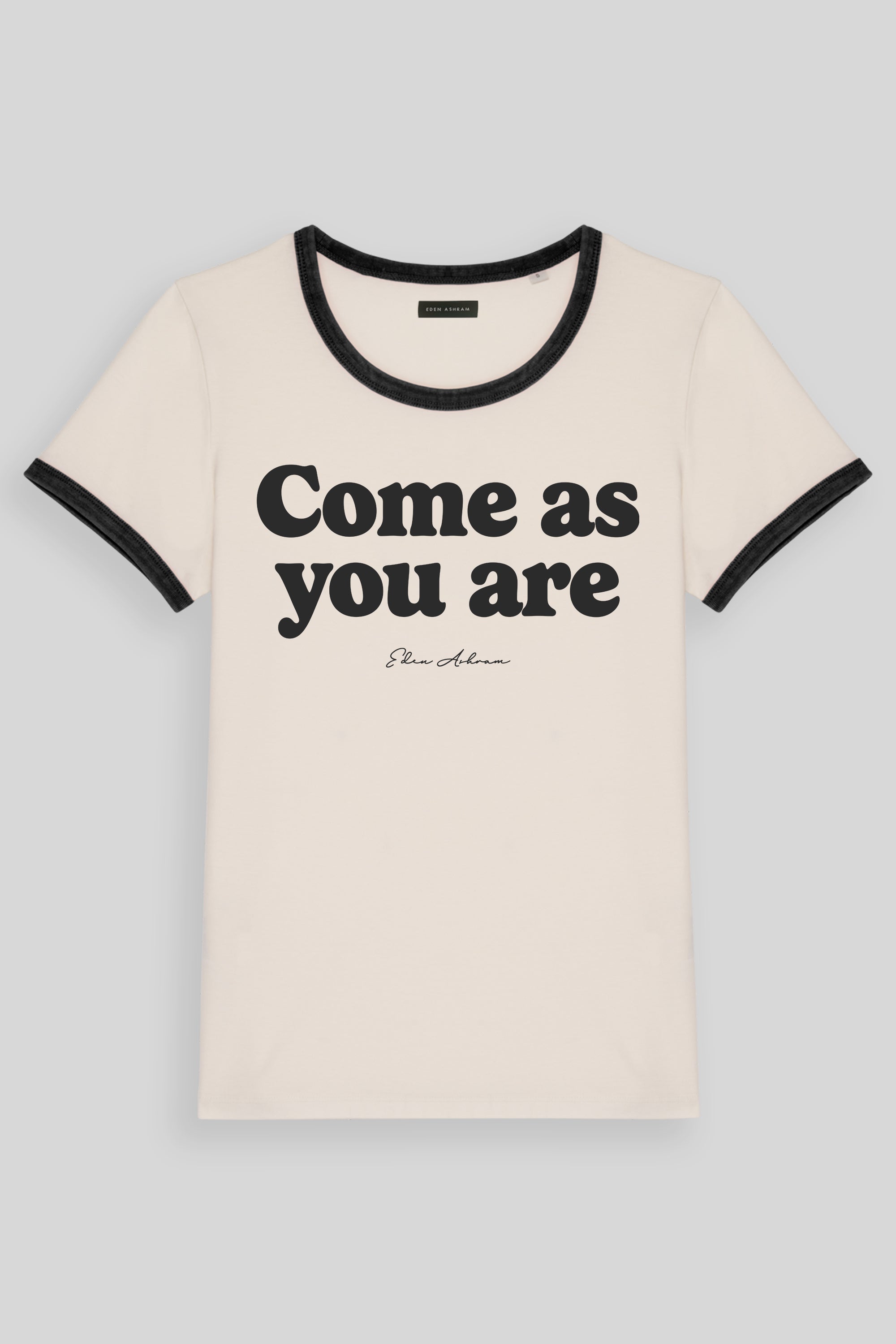 An off-white ringer t-shirt with black trim on the crew neck and sleeve cuffs, featuring the text 'Come as you are' in black across the chest, on a light gray background.